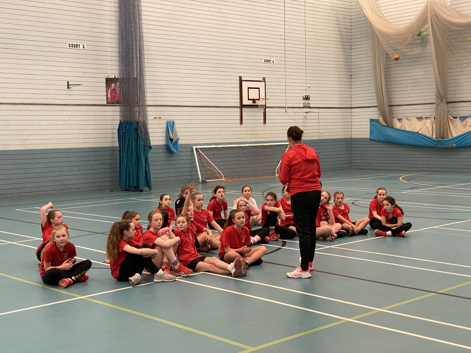 A coach talking to a squad of Saddleworth players sitting on the court